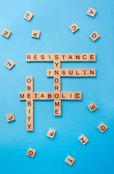 Crossword puzzle about insulin resistance made of wooden blocks with letters on blue background. Vertical banner, selective focus